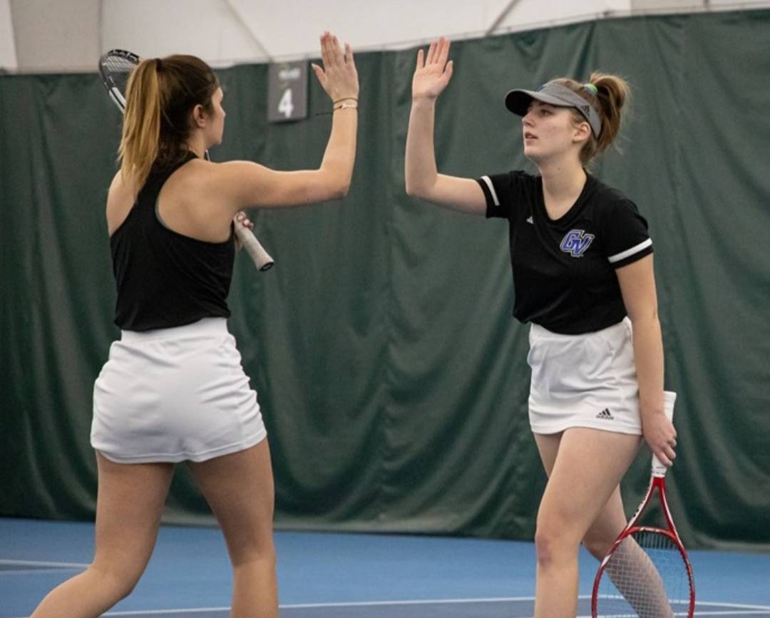 Tennis teammates giving a high five on the court.